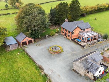 An outdoor view of a house with a garage and fountain at Bwthyn Ty Newydd in Llangadfan