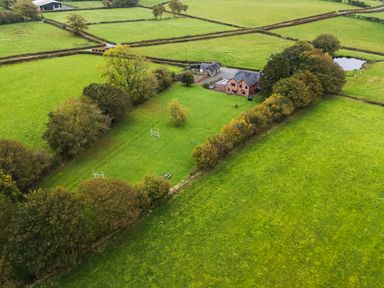 An aerial view of a house and farm surrounded by fields at Bwthyn Ty Newydd Llangadfan