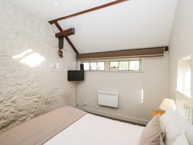 A bedroom with a bed pillows and a wall mounted TV at Old Cart Shed Lyneham near Royal Wootton Bassett