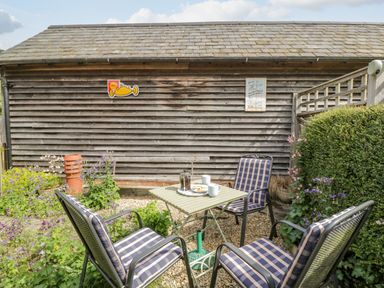 An outdoor seating area with four chairs around a small table in a gravel garden at Old Cart Shed in Lyneham near Royal Wootton Bassett