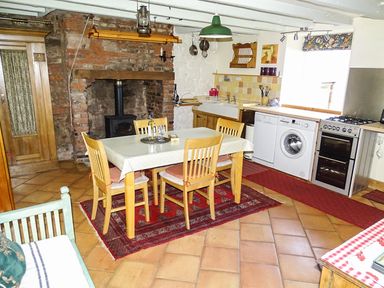 A kitchen with a dining table and chairs a fireplace and kitchen appliances at The Lookout in Berwick-upon-Tweed
