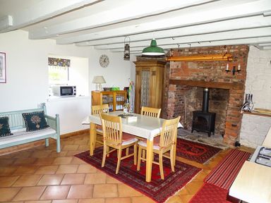 A dining area with wooden table and chairs near a brick fireplace and a blue bench at The Lookout in Berwick-upon-Tweed