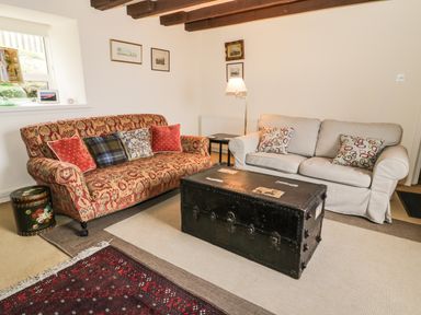 A living room with two sofas a large black trunk coffee table and framed pictures on the wall at The Lookout in Berwick-upon-Tweed