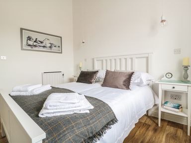 A bedroom with a white bed frame two brown pillows folded towels on a blanket and two bedside tables at The Stable in Berkeley