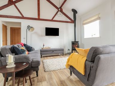A living room with two grey sofas a wood stove and a television mounted on the wall at The Stable in Berkeley