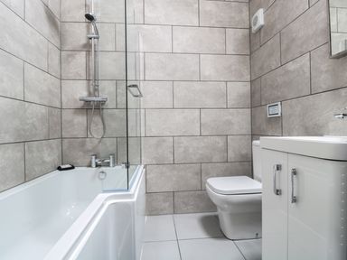 A bathroom with a bathtub shower toilet and sink cabinet at The Stable in Berkeley