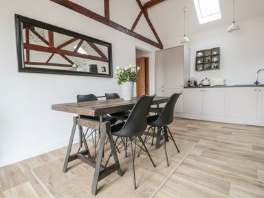 A dining area with a wooden table and black chairs under wooden beams and skylights at The Stable in Berkeley