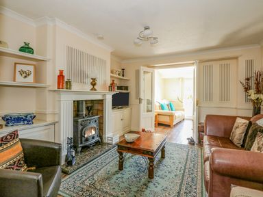 A living room with a wooden coffee table a fireplace and sofas at Camerons Cottage in Swaffham