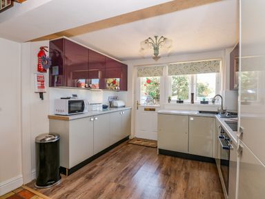 A kitchen with cabinets appliances a microwave a fire extinguisher and a door with windows at Camerons Cottage in Swaffham
