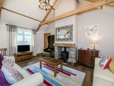 A living room with two sofas wooden coffee table and a stone fireplace at Warbrook in Bradworthy