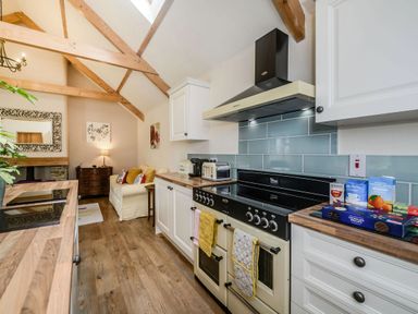 A kitchen with wooden countertops a stove a toaster and a seating area with a sofa at Warbrook in Bradworthy