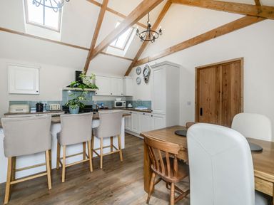 A kitchen with wooden beams on the ceiling and bar stools at a counter at Warbrook in Bradworthy