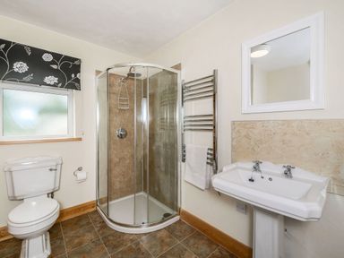 A bathroom with a toilet shower cubicle sink mirror and heated towel rail at Warbrook in Bradworthy