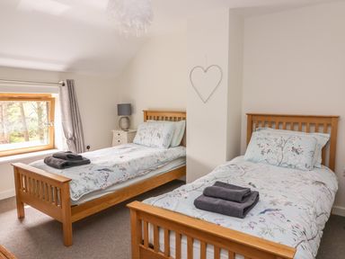 A bedroom with two single beds with floral bedding and folded towels at The Farmhouse in Capel Bangor near Aberystwyth