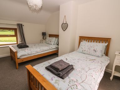 A bedroom with two single beds with floral bedding and folded towels on them at The Farmhouse in Capel Bangor near Aberystwyth