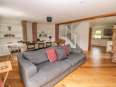 A living room with a gray sofa and dining table with wooden chairs near a staircase and an open kitchen at The Farmhouse in Capel Bangor near Aberystwyth