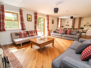 A living room with sofas around a wooden coffee table and plaid curtains at The Farmhouse in Capel Bangor near Aberystwyth