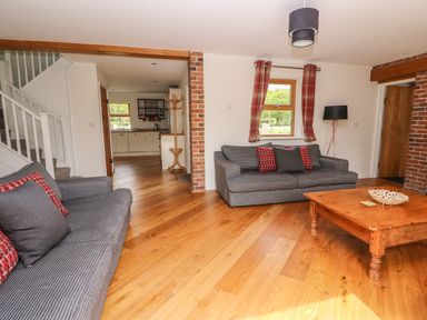 A living room with two gray sofas and a wooden coffee table with a kitchen visible in the background at The Farmhouse in Capel Bangor near Aberystwyth