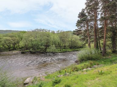 A river flowing with trees along its banks and grassy area at The Farmhouse in Capel Bangor near Aberystwyth