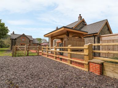 An outdoor area with wooden fencing gravel ground and stone houses at The Farmhouse in Capel Bangor near Aberystwyth