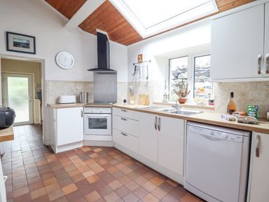 A kitchen with white cabinets a built in oven a dishwasher a sink and a skylight at Haulfryn in Bethesda