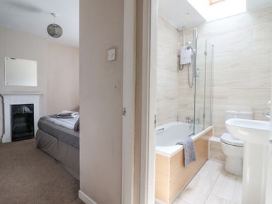 A bedroom with a bed and fireplace next to a bathroom with a bathtub toilet and sink at Haulfryn in Bethesda