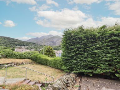 A garden with trimmed hedges stone wall and mountains in the background at Haulfryn in Bethesda