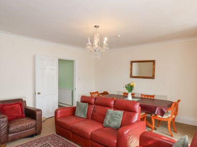 A living room with red and brown leather sofas a dining table with chairs and flowers on it at Mayfield Manor Whitby