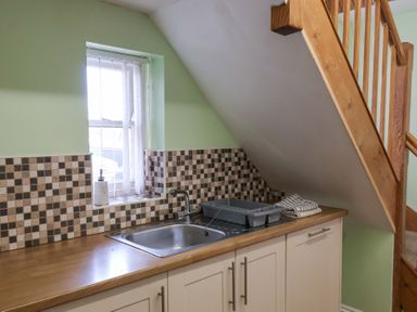 A kitchen sink with a drying rack and towels under a staircase at Mayfield Manor in Whitby