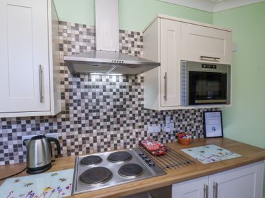 A kitchen counter with stovetop kettle oven and tiled backsplash at Mayfield Manor in Whitby
