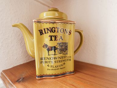 A yellow ceramic teapot with Ringtons Tea branding on a wooden surface at Mayfield Manor in Whitby