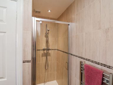 A tiled bathroom with a glass shower enclosure and a pink towel on a metal towel rack at Mayfield Manor in Whitby
