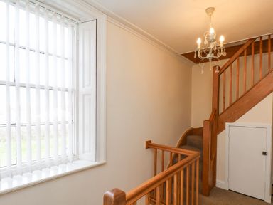 A staircase with wooden railings and a window with vertical blinds at Mayfield Manor in Whitby