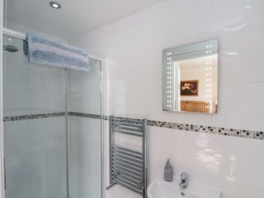 A bathroom with a glass shower enclosure a towel rail a sink and a mirror reflecting part of another room at Mayfield Manor in Whitby