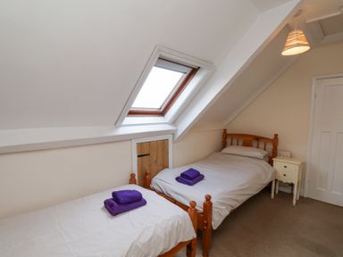 A bedroom with two single wooden beds under a sloped ceiling and a skylight window at Mayfield Manor in Whitby