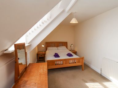 A bedroom with a double bed two bedside tables with lamps a wooden dressing table with a mirror and a radiator on the wall at Mayfield Manor Whitby