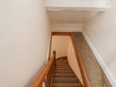 A carpeted staircase with wooden handrails and beige walls at Mayfield Manor in Whitby
