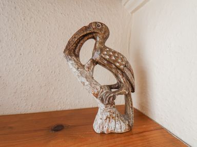 A wooden shelf with a carved wooden bird sculpture against a textured white wall at Mayfield Manor Whitby