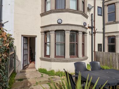A stone exterior wall with windows and an open door leading inside a building a black outdoor table and chairs on a stone patio at Mayfield Manor in Whitby