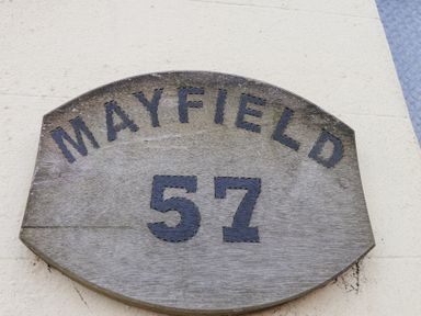 A wooden plaque with the word Mayfield and number 57 on a light wall at Mayfield Manor in Whitby