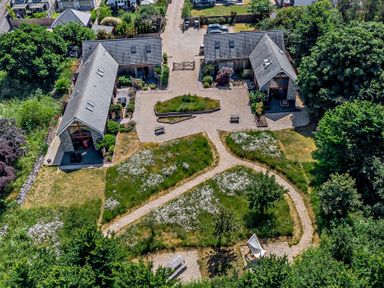 Aerial view of two modern stone houses with pitched roofs surrounded by gardens and pathways at Budmouth in Upwey near Weymouth