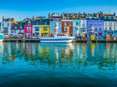 A waterfront with colorful buildings and a docked boat at Budmouth in Upwey near Weymouth