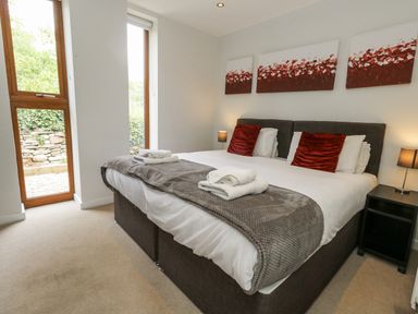 A bedroom with a double bed and windows at Budmouth in Upwey near Weymouth