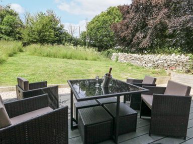 A table with chairs and a bottle cooler in a garden at Budmouth Upwey near Weymouth