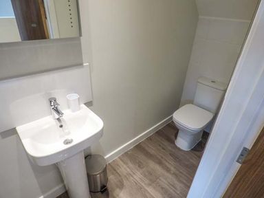 A bathroom with a pedestal sink a trash can and a toilet at Bramshurst in Upwey near Weymouth
