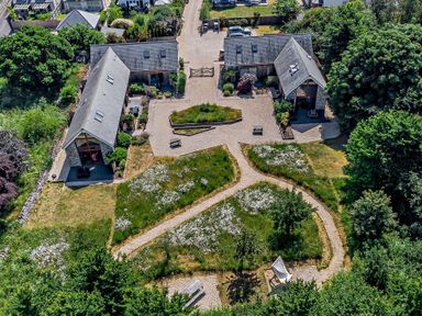 Aerial view of two buildings with gray roofs surrounded by paths benches and grassy areas with trees at Bramshurst Upwey near Weymouth