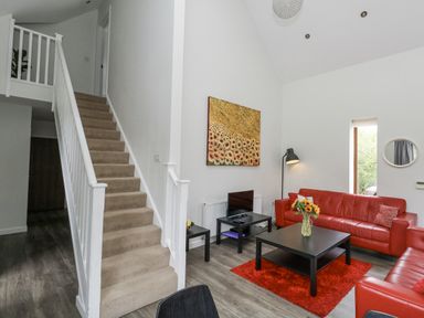 A living room with a red sofa and a staircase at Everdene Upwey near Weymouth