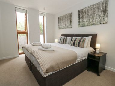 A bedroom with a bed and two windows at Everdene Upwey near Weymouth