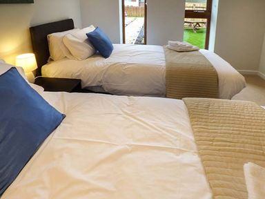 A bedroom with two single beds with white bedding and blue pillows at Casterbridge Upwey near Weymouth