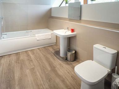 A bathroom with a bathtub a sink a toilet and a small waste bin at Casterbridge Upwey near Weymouth